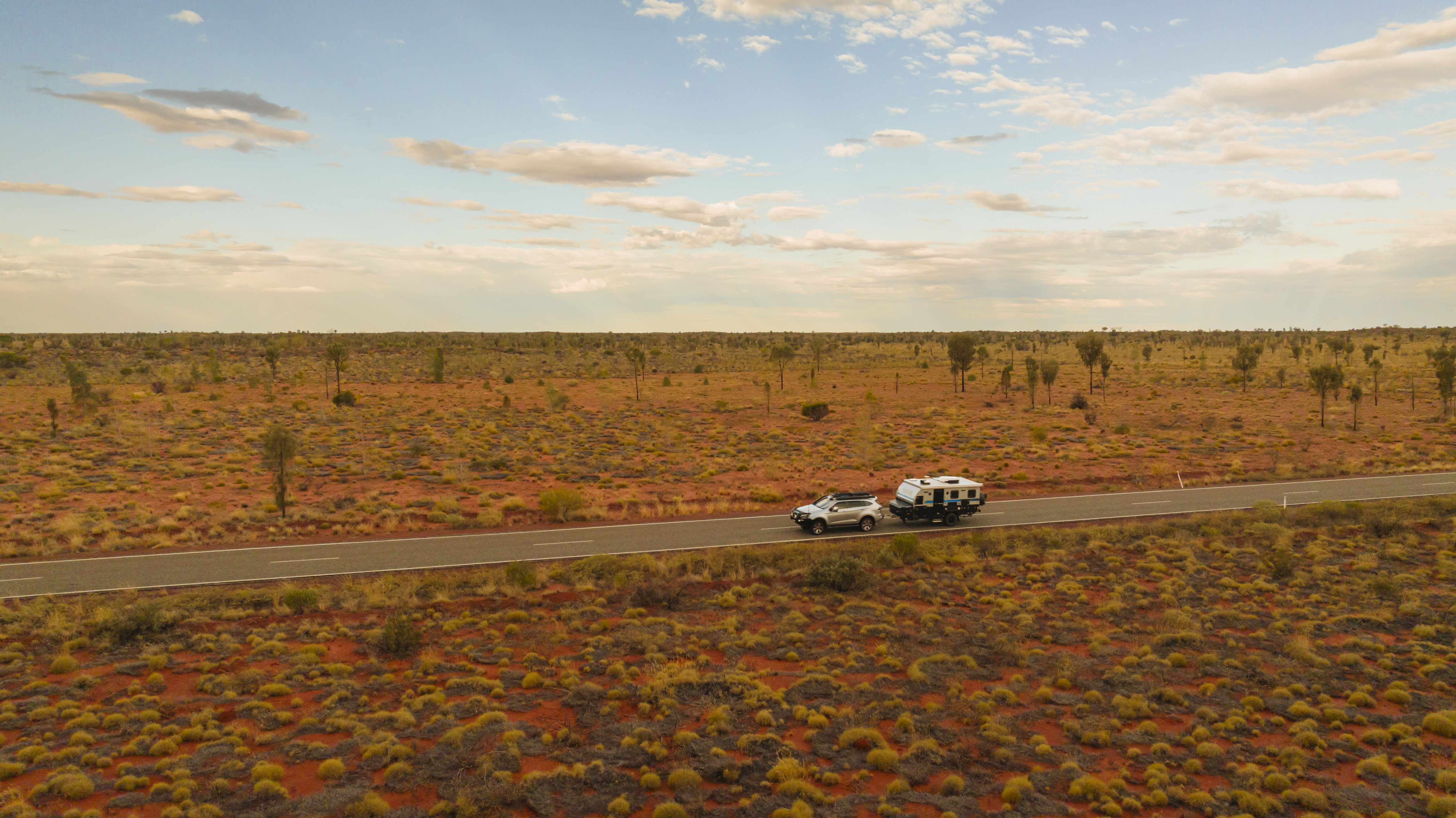 car with camper driving down a desert road